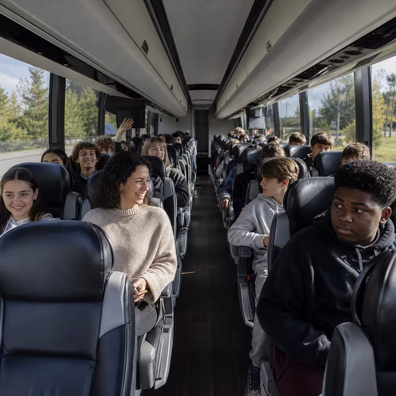 Group boarding a white charter bus for School Transportation transportation in Austin