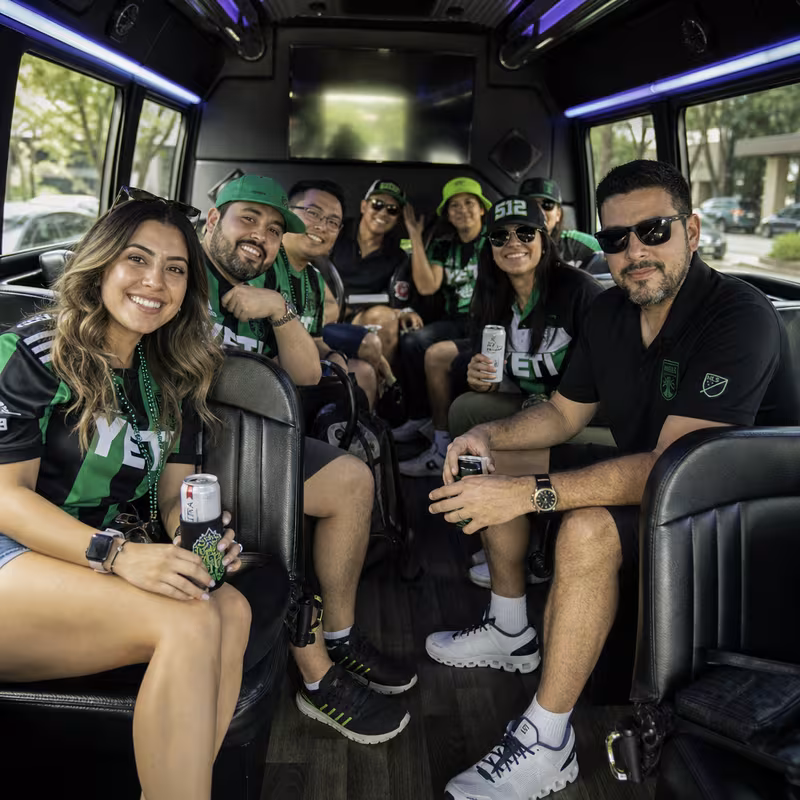 Group boarding a white charter bus for Sporting Event Transportation transportation in Austin